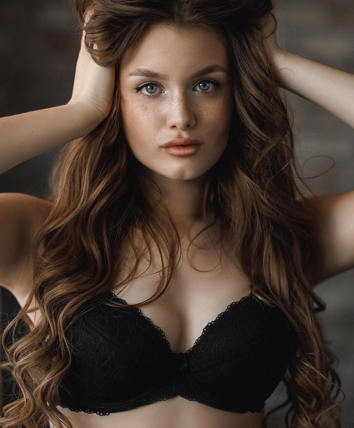 Model with long hair wearing black lingerie.