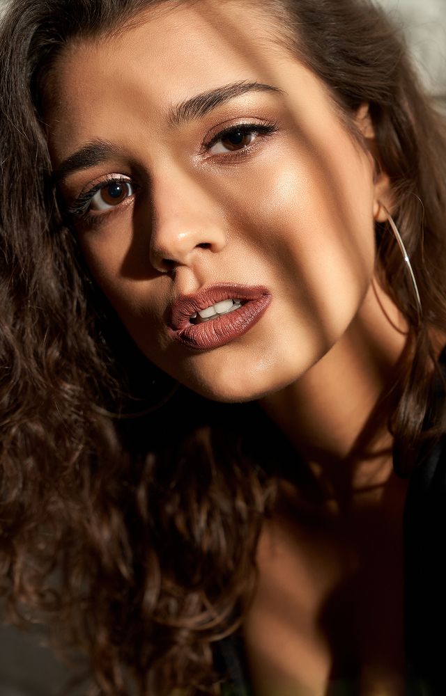 Woman with curly hair holding her face.