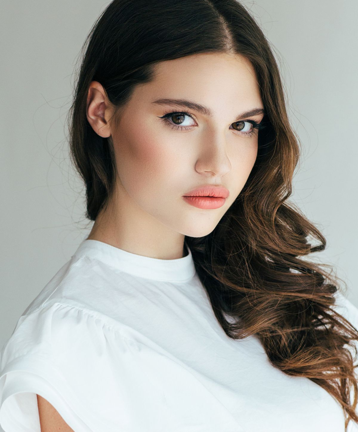 Model with long hair wearing a white top.