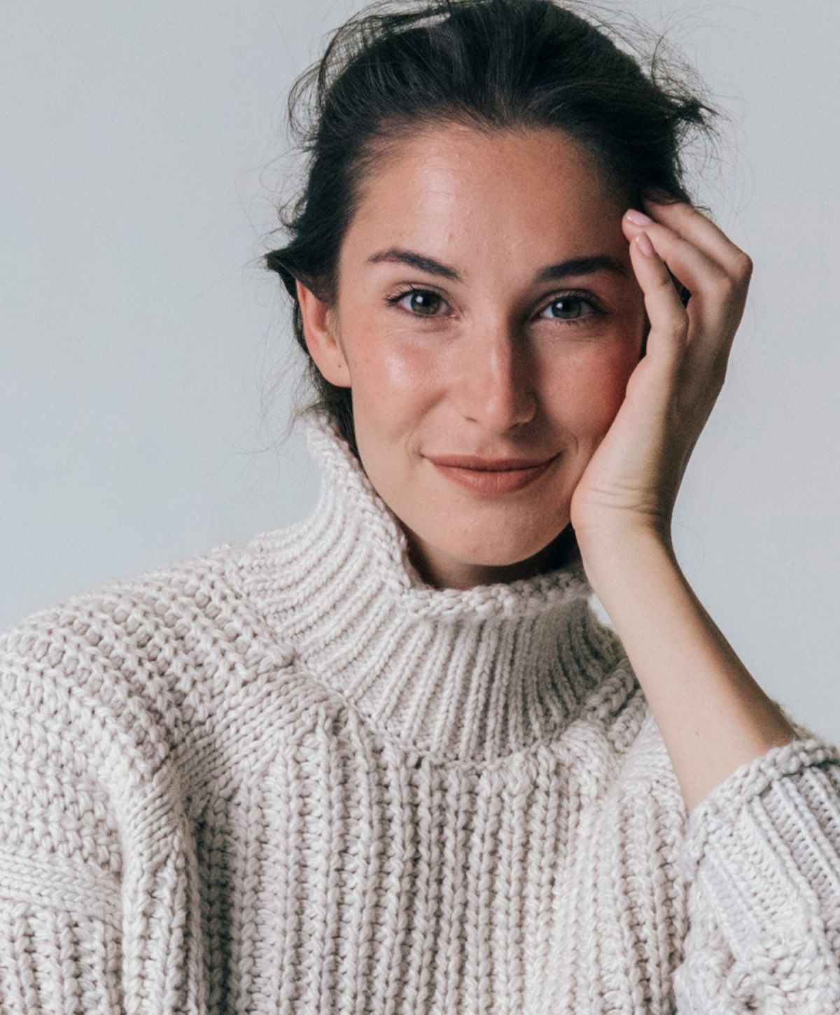 Woman smiling in a cozy white sweater.
