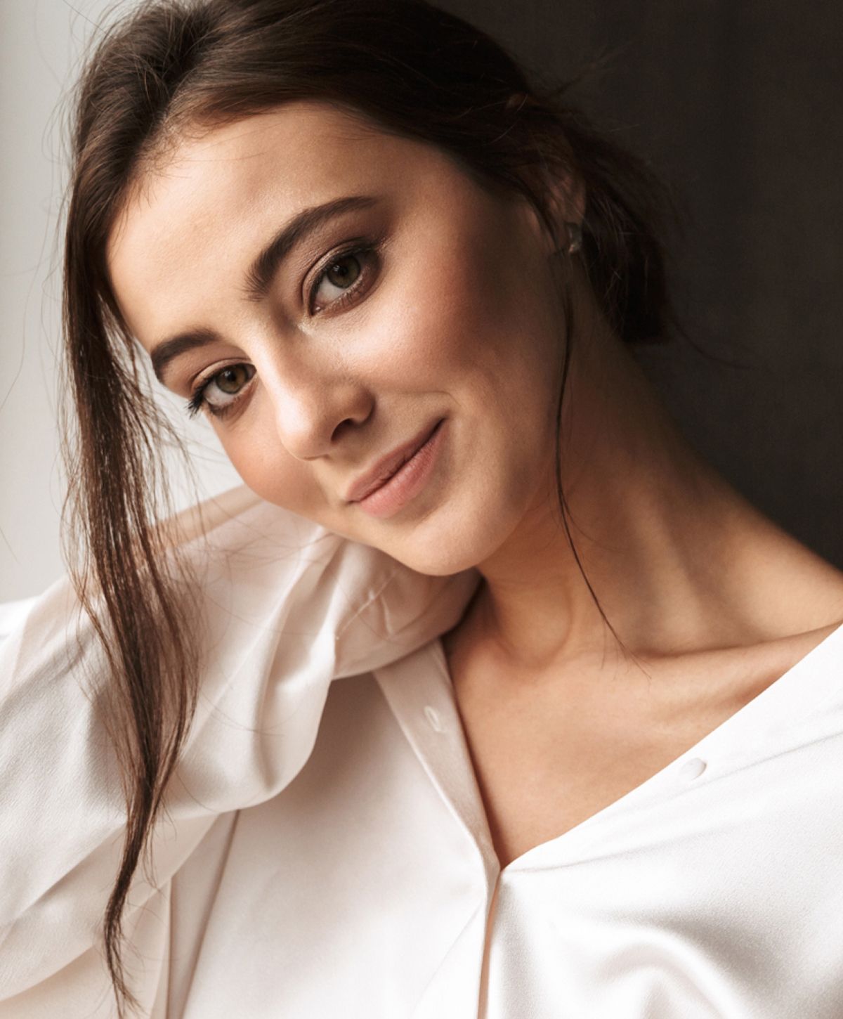 Woman wearing a white blouse, smiling softly.