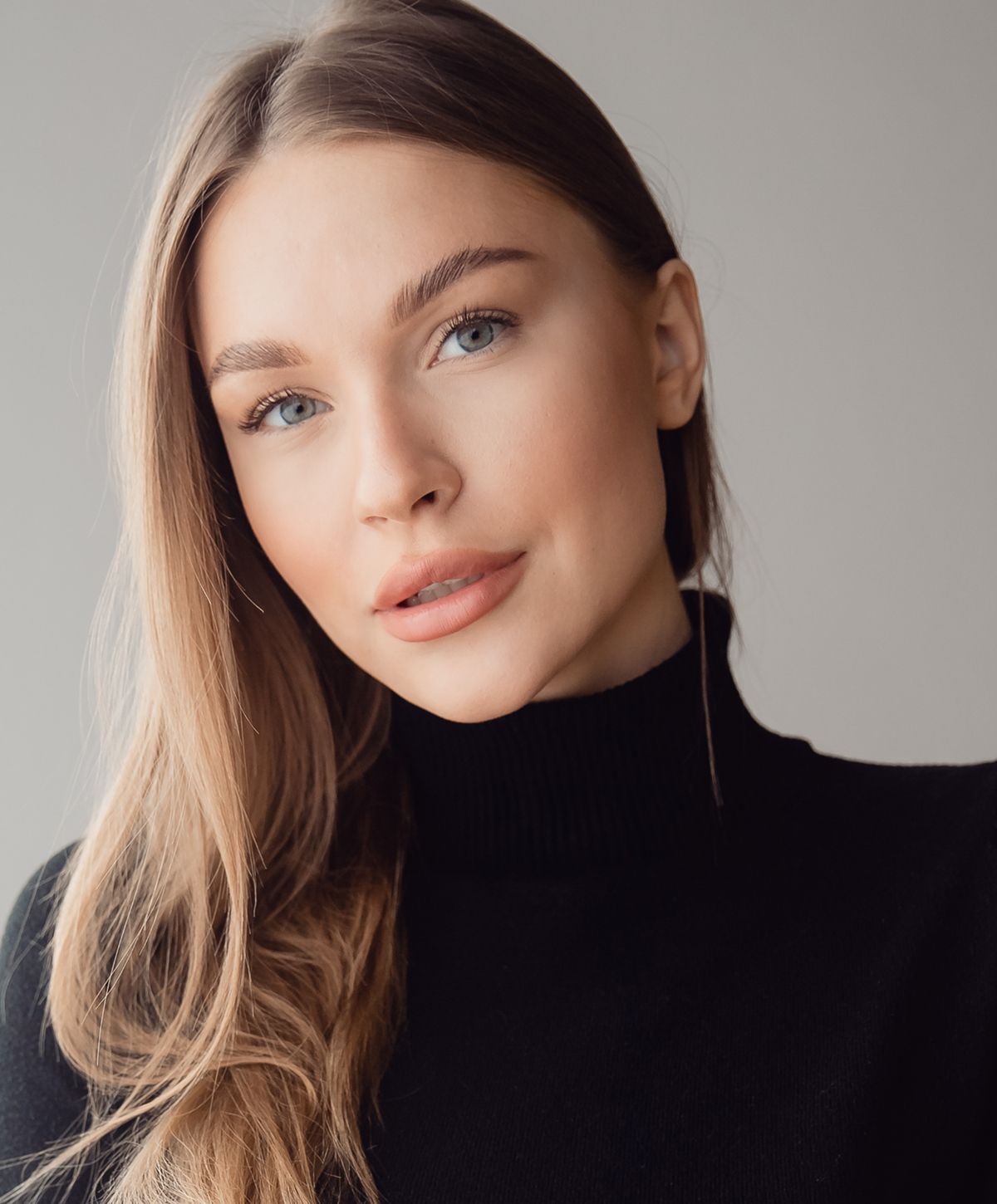 Young woman with long hair in black turtleneck.