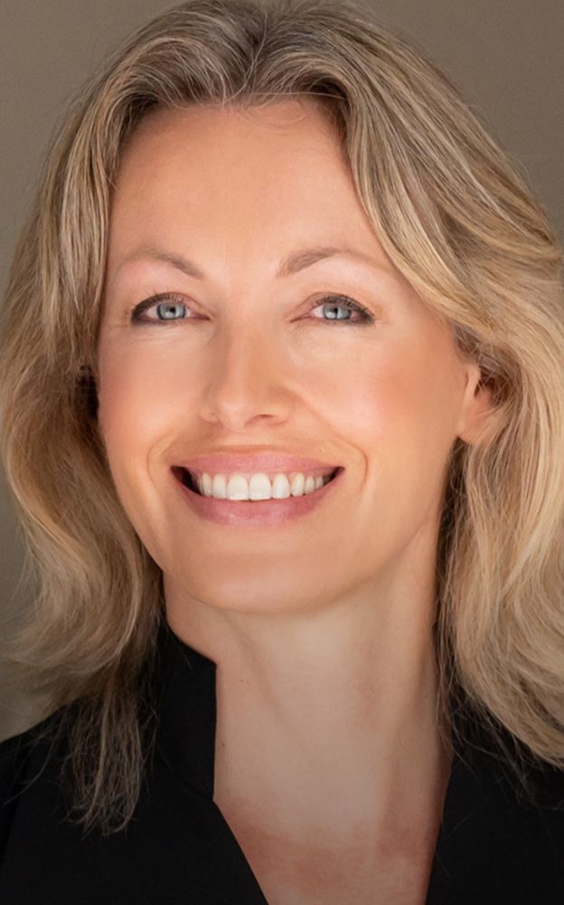 Smiling woman with blonde hair and light eyes.