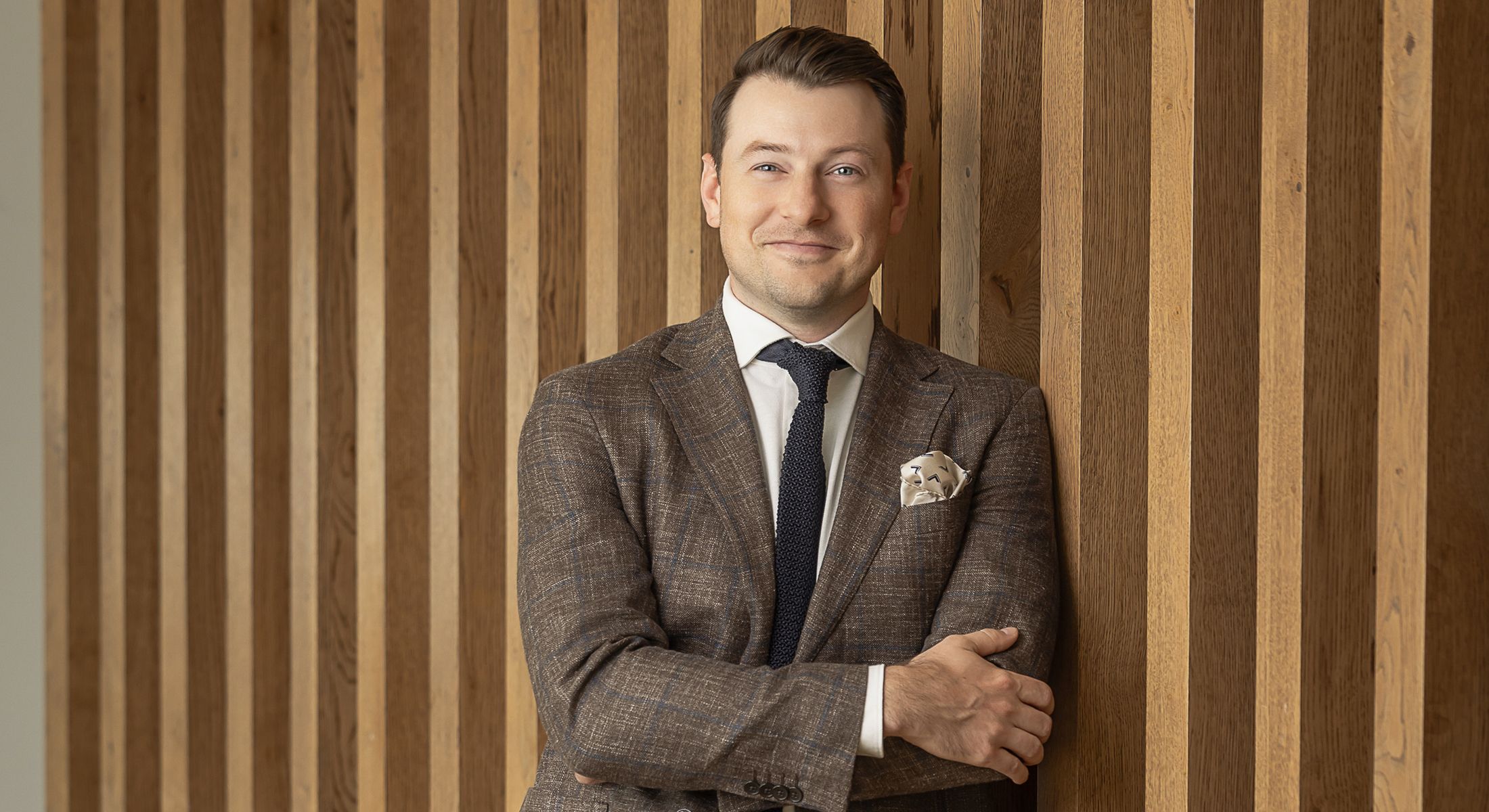 Professional man leaning against wooden wall.