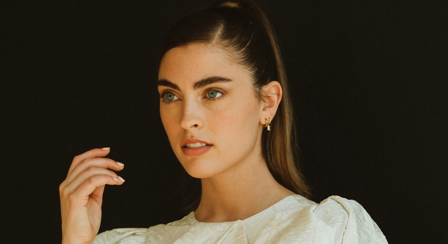 Woman with green eyes against black background.