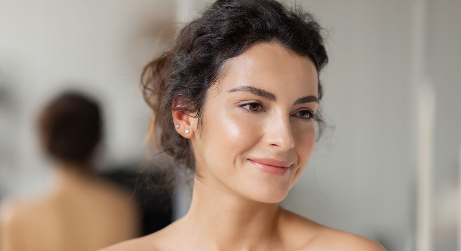 Smiling woman with natural makeup, soft background.